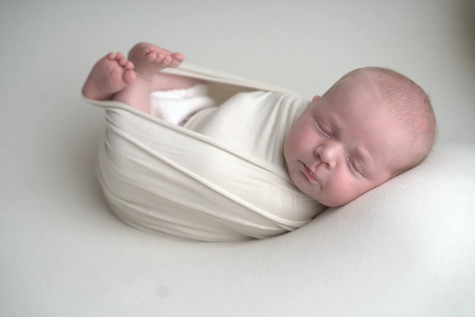 Wrapped newborn sleeping peacefully in cream