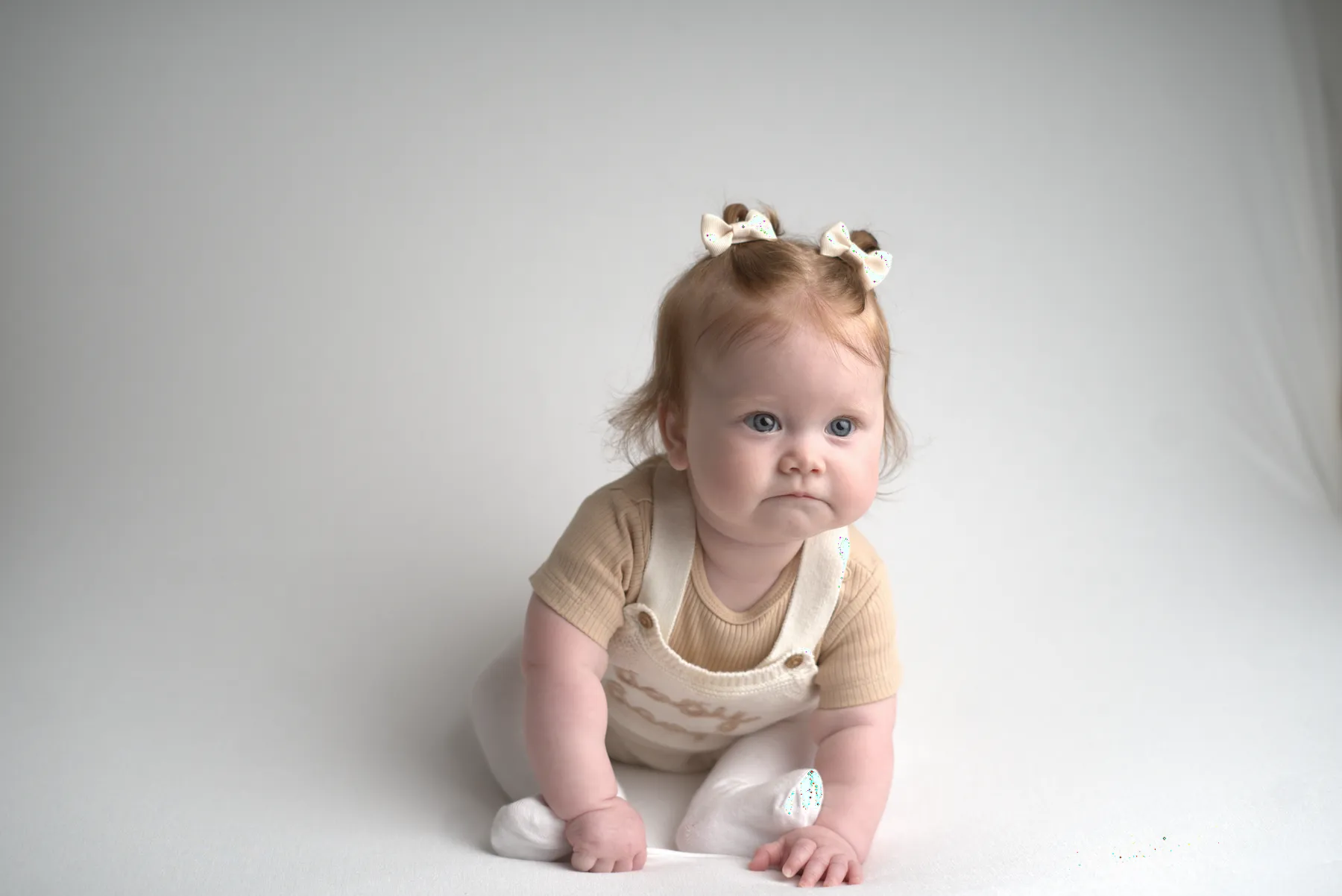 Baby crawling forward in a neutral studio setting