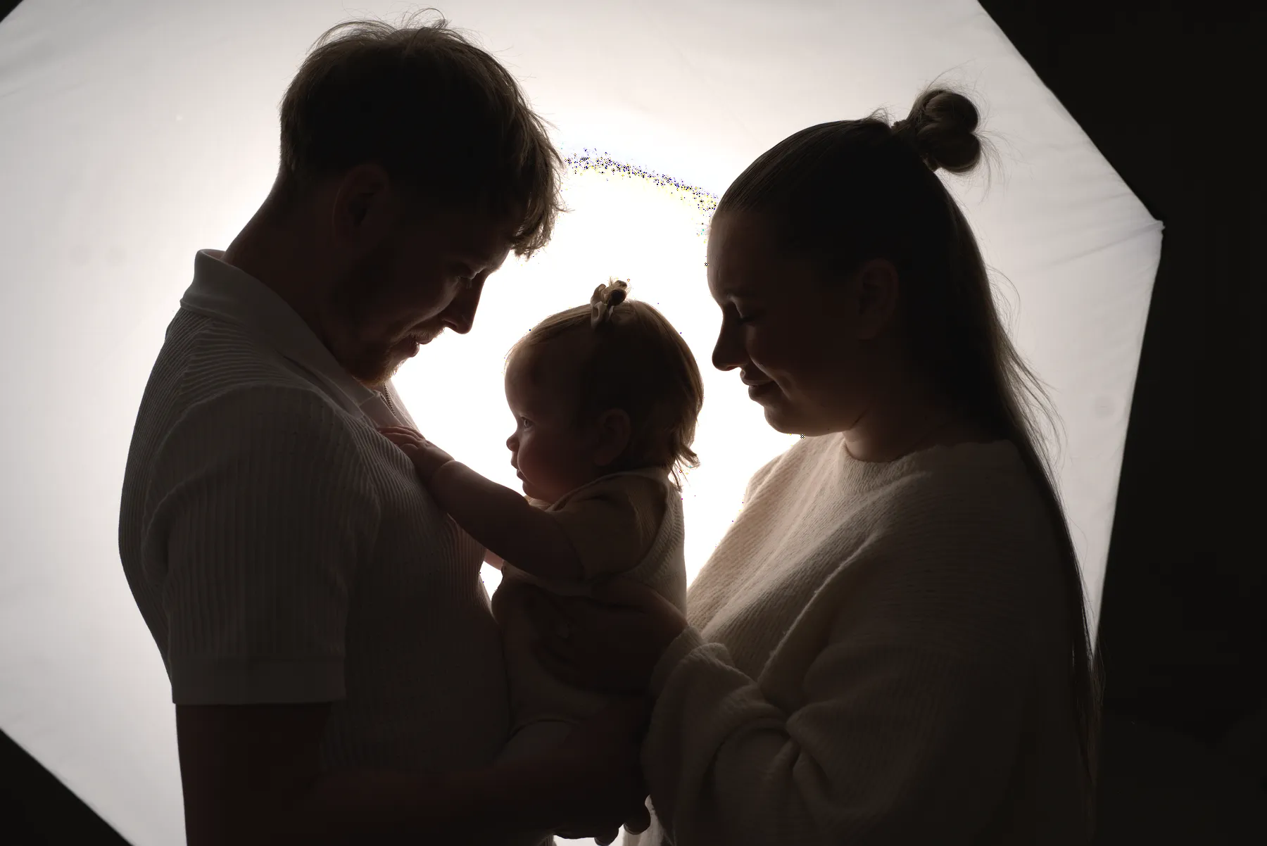 Backlit family silhouette holding their baby