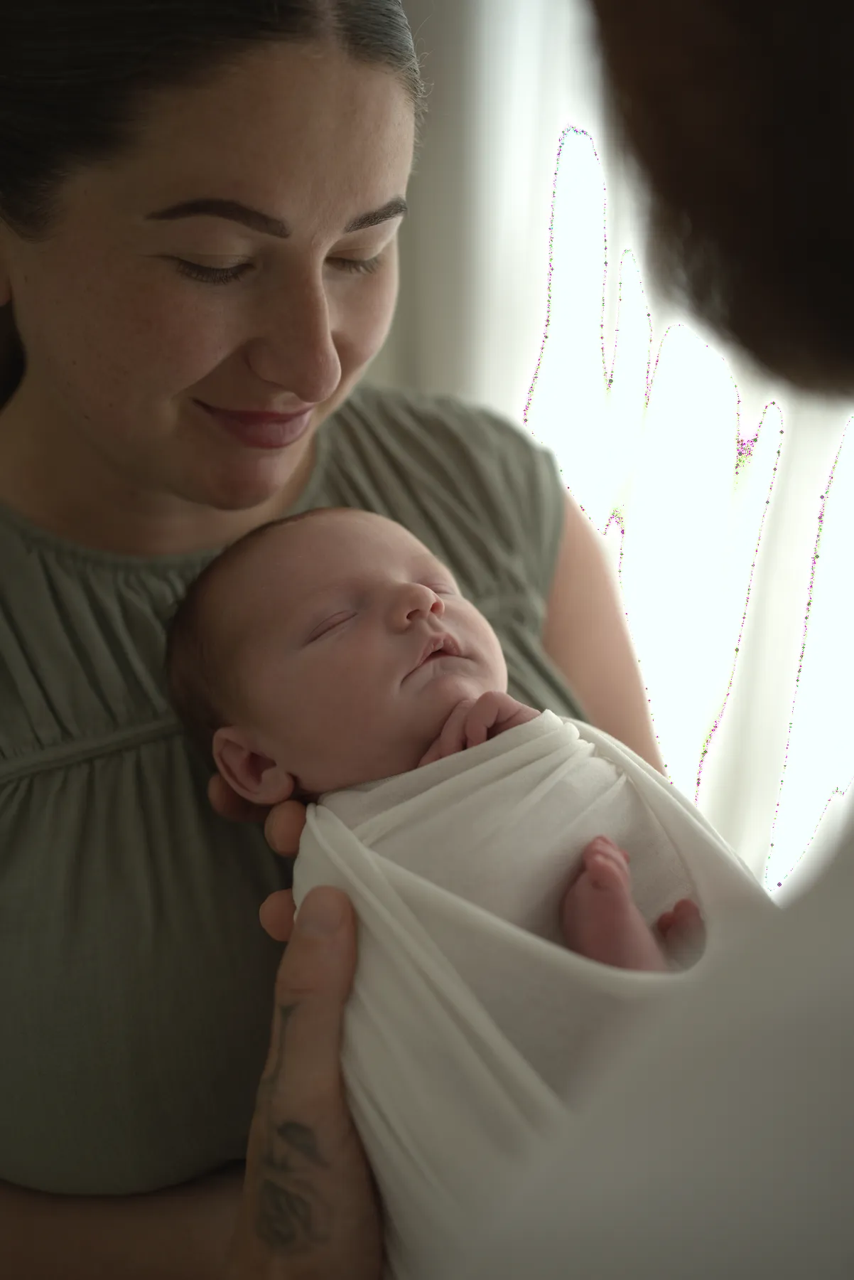 Mother cradling her sleeping wrapped newborn