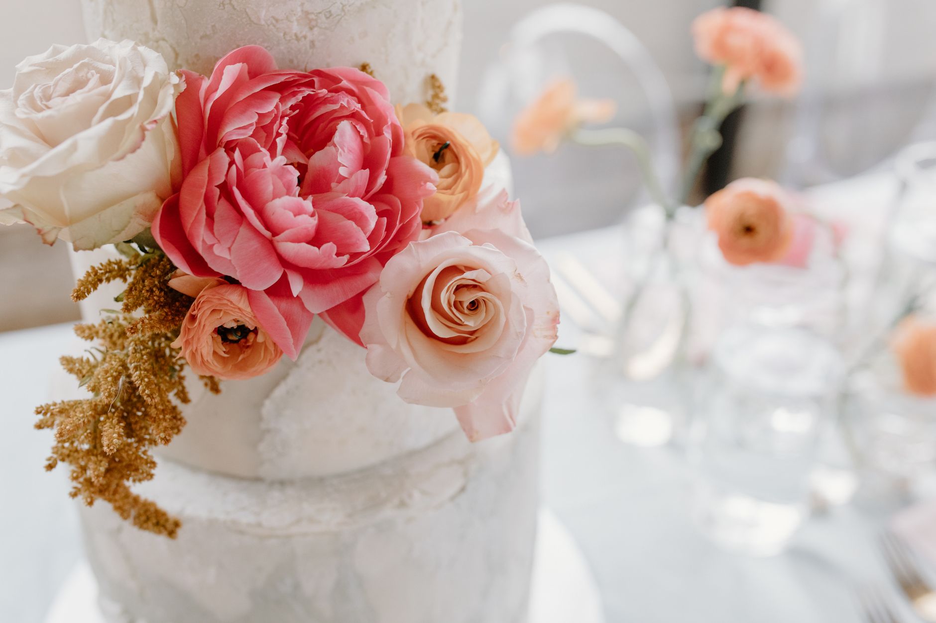 White celebration cake finished with fresh pink and cream flowers