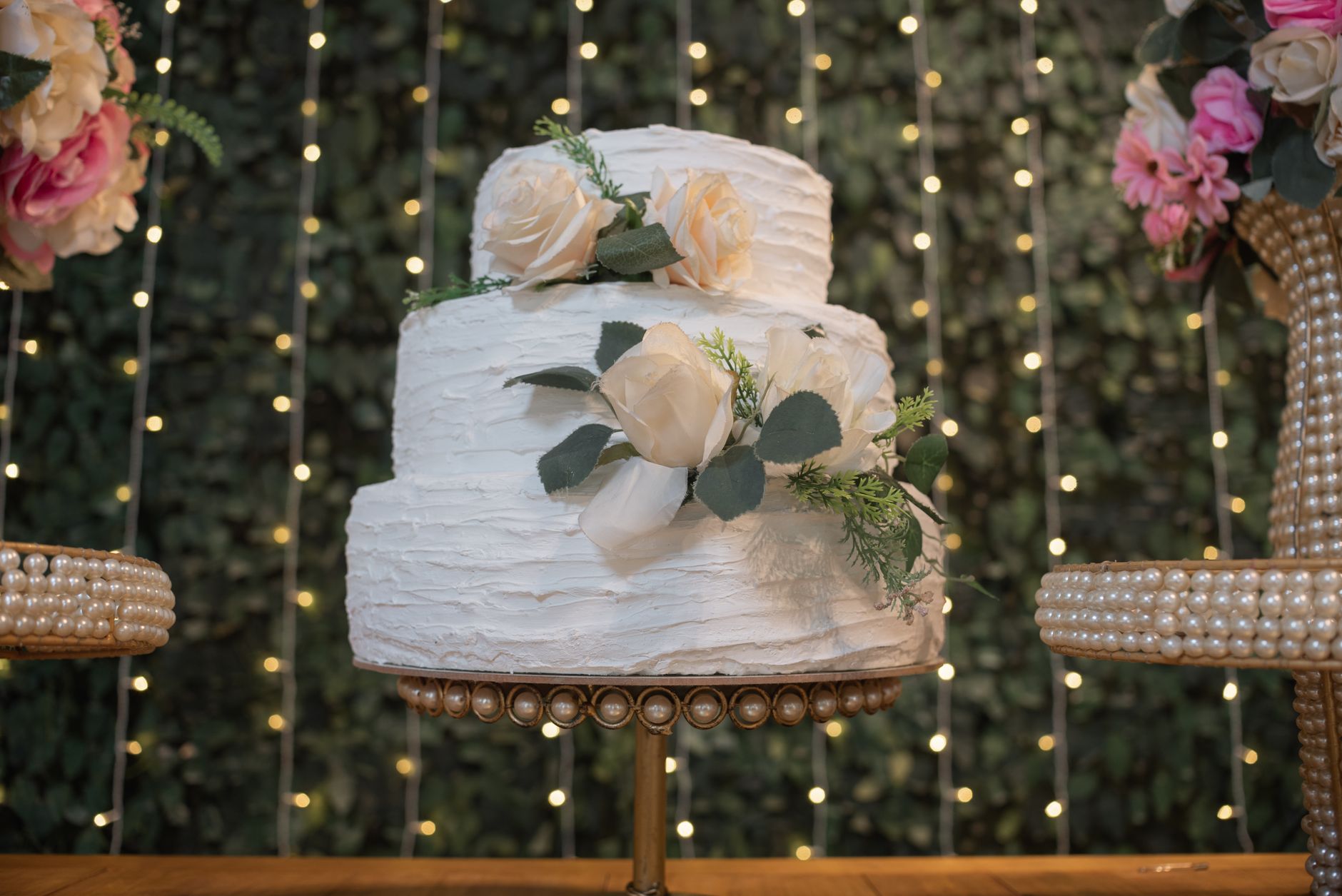 Three tier white celebration cake with cream roses and foliage